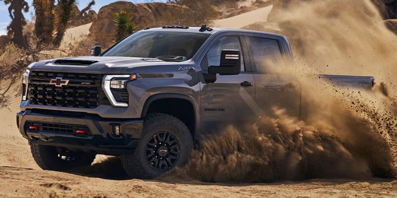 Red Chevrolet Silverado 2500HD driving on a dirt trail.