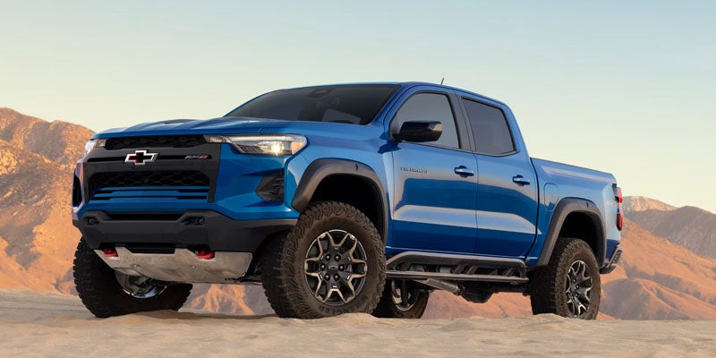 Blue Chevrolet Colorado truck parked on desert terrain.