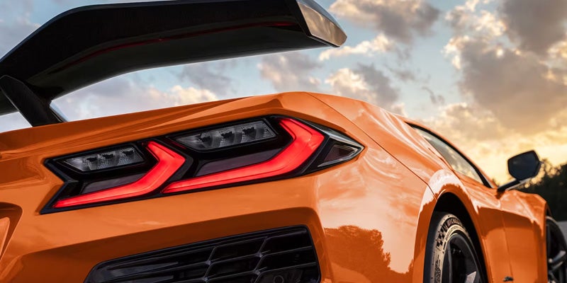 Corvette Z06 rear with illuminated red taillights and raised trunk lid.
