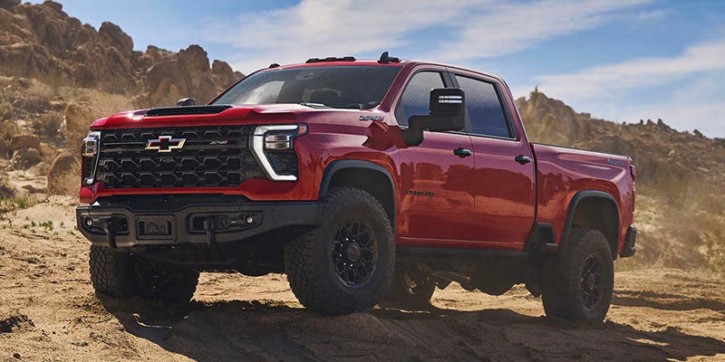 Red Chevrolet Silverado truck parked on a dusty trail