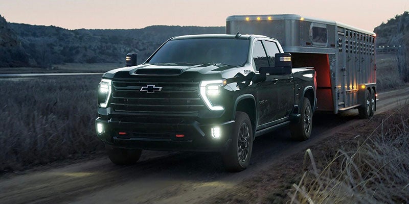 Dark Chevrolet Silverado truck towing a large trailer